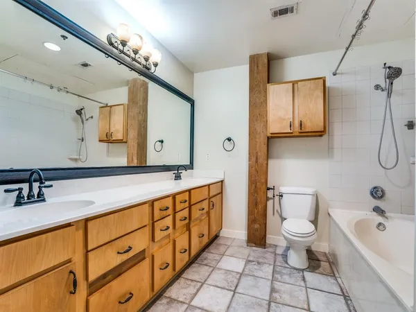 a spacious bathroom with a double vanity sink toilet mirror and bathtub