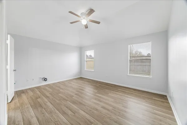 an empty room with wooden floor and windows