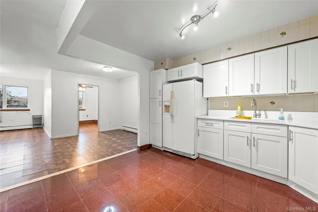 a view of a kitchen with a sink and dishwasher with white cabinets