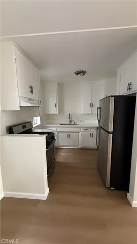 a kitchen with a refrigerator a stove and white cabinets