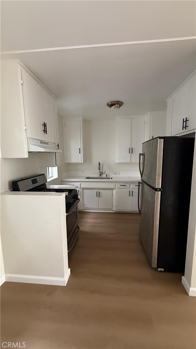 1345 Anaheim Street, Unit 2 Harbor City, CA 90710 - Photo 12 of 16 a kitchen with a refrigerator a stove and white cabinets