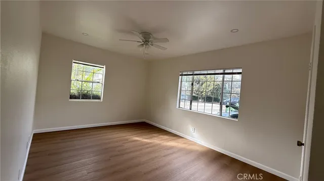 a view of an empty room with a window and wooden floor