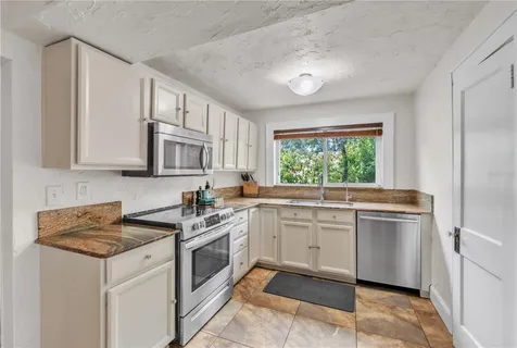 a kitchen with stainless steel appliances granite countertop a stove a sink and a microwave