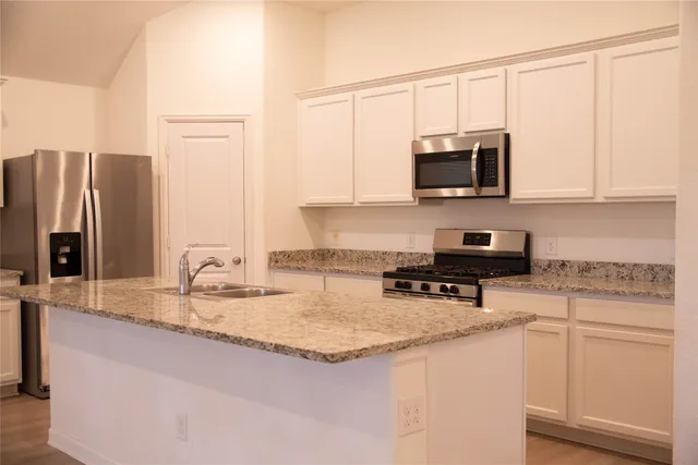a kitchen with stainless steel appliances granite countertop a sink a stove and microwave