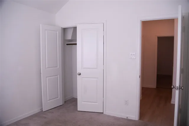 a view of an empty room with closet and wooden floor