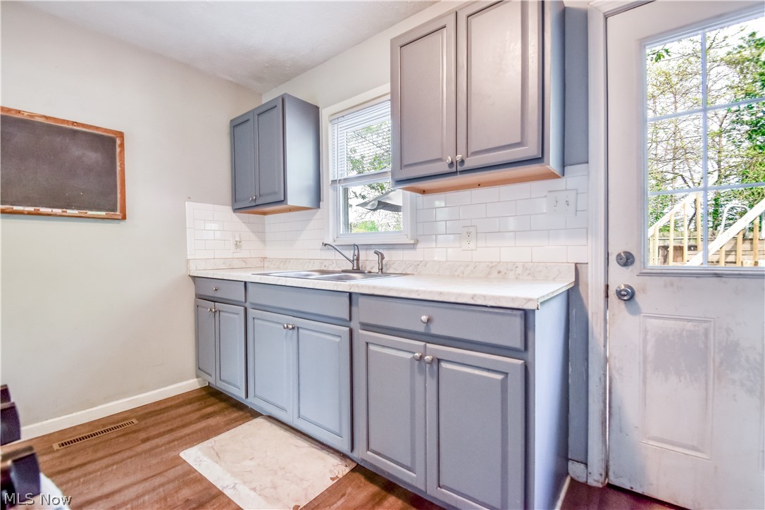 1969 Paisley Road Madison, OH 44057 - Photo 3 of 20 Kitchen space featuring gray shaker-style cabinetry, white subway tile backsplash, and light-toned countertops