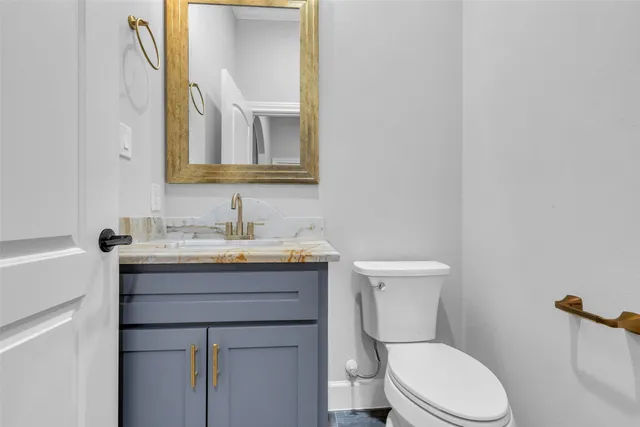 a bathroom with a toilet a sink a mirror and vanity