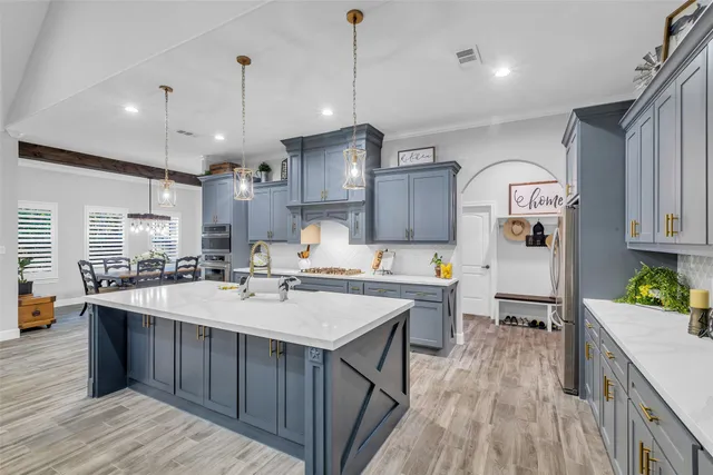 a large kitchen with lots of counter space a sink appliances and cabinets