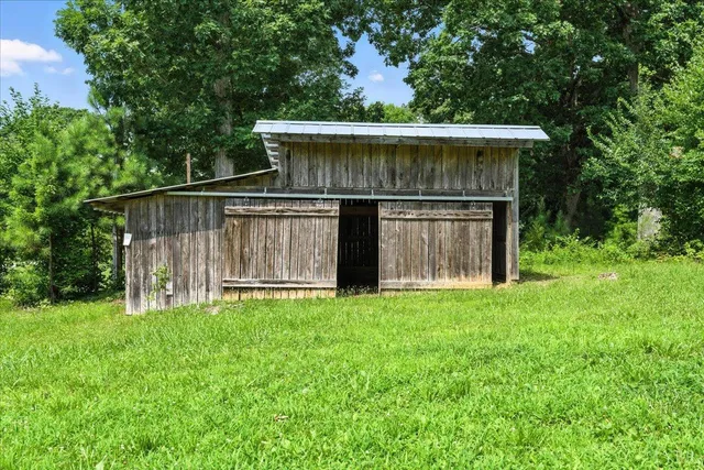 a view of a wooden house with a big yard and large trees