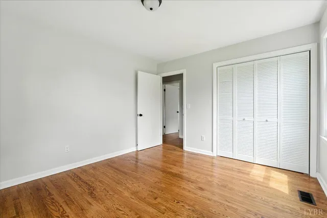 a view of an empty room with wooden floor and closet area