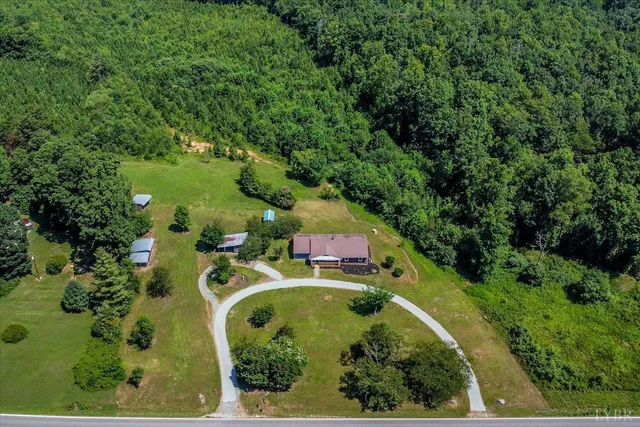 an aerial view of residential house with outdoor space and trees all around