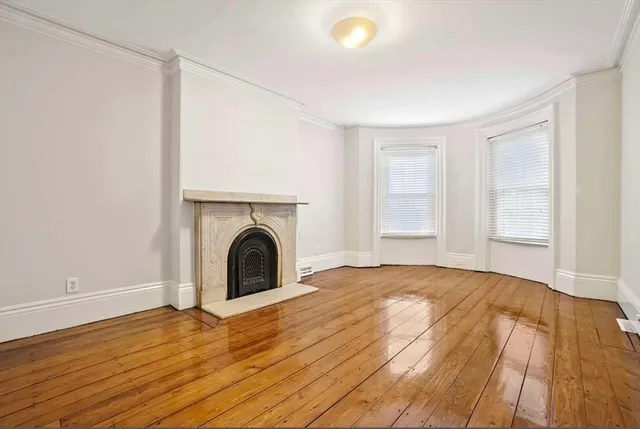 a view of empty room with wooden floor and fireplace