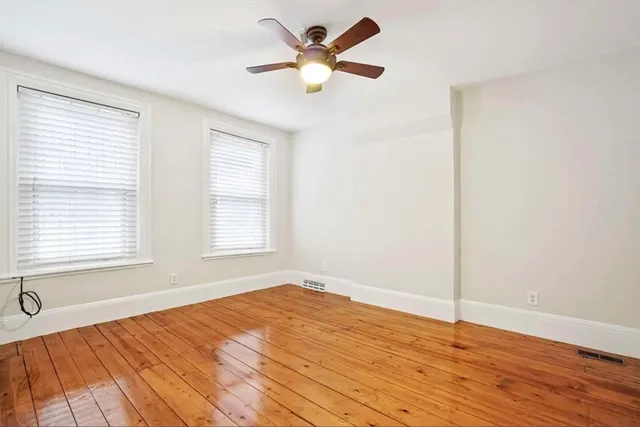 a view of an empty room with window and a chandelier fan
