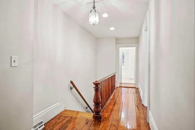 a view of a hallway with wooden floor and staircase