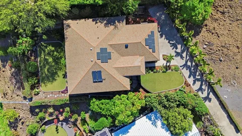 an aerial view of a house with swimming pool and large trees