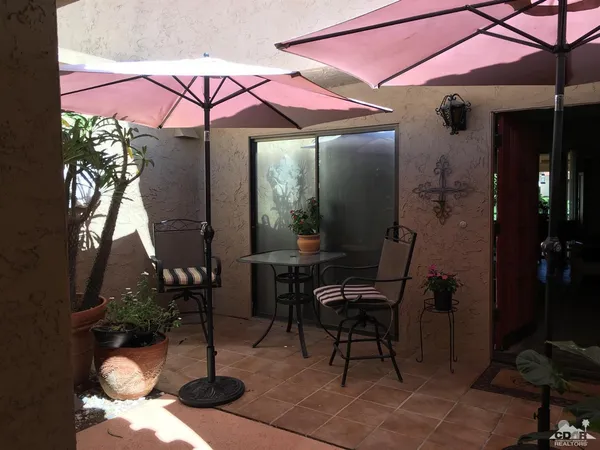 a view of a patio with table and chairs under an umbrella