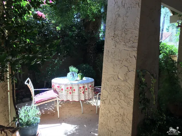 a patio with table and chairs and potted plants