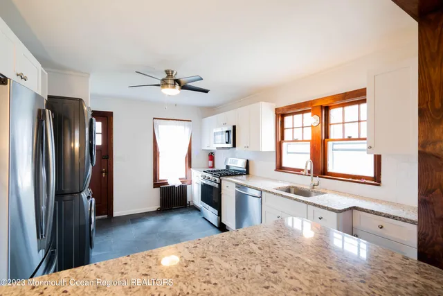 a kitchen with stainless steel appliances kitchen island granite countertop a refrigerator a sink dishwasher a stove and a dining table with wooden floor