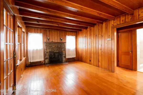 an empty room with windows a fireplace and wooden floor