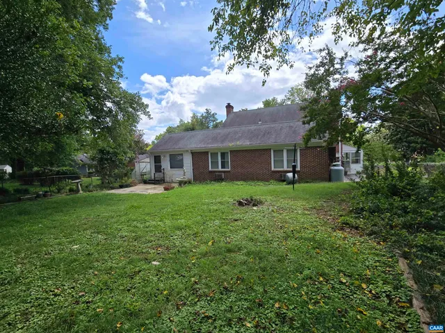 a view of a yard in front of a house with a large tree