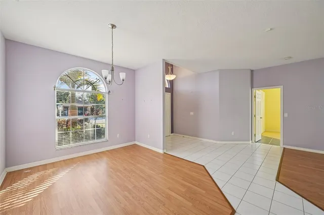 a view of an empty room with window and chandelier