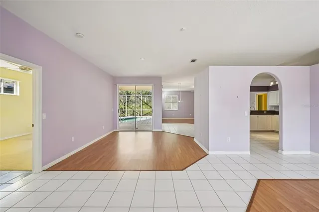 a view of an empty room with window and wooden floor