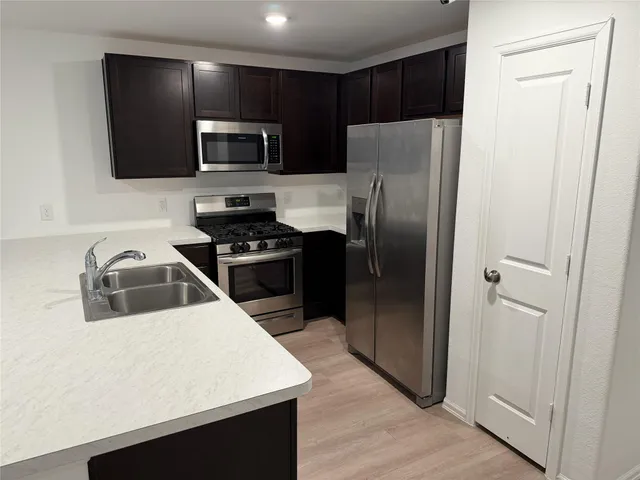 a kitchen with a refrigerator a microwave a sink and cabinets