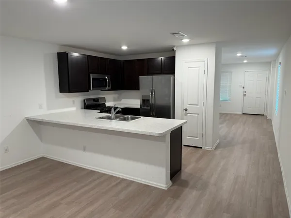 a view of kitchen with stainless steel appliances refrigerator stove microwave and cabinets