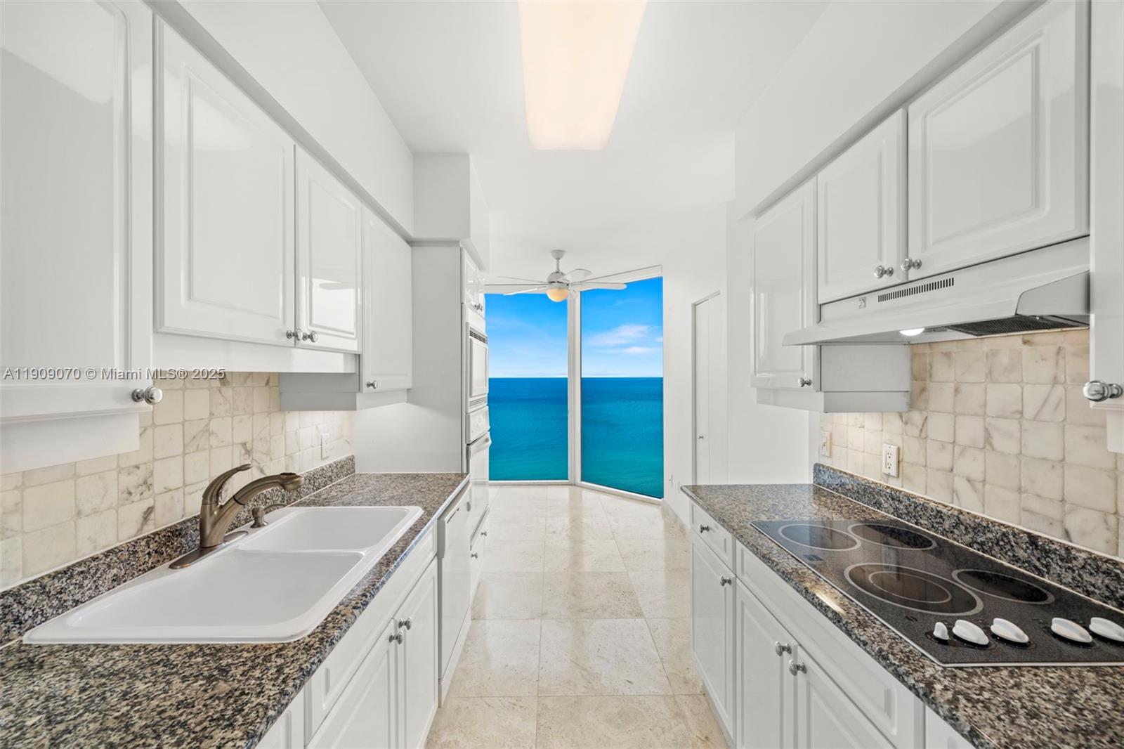 4775 Collins Avenue, Unit 1903 Miami Beach, FL 33140 - Photo 10 of 49 a kitchen with granite countertop a sink stove and cabinets