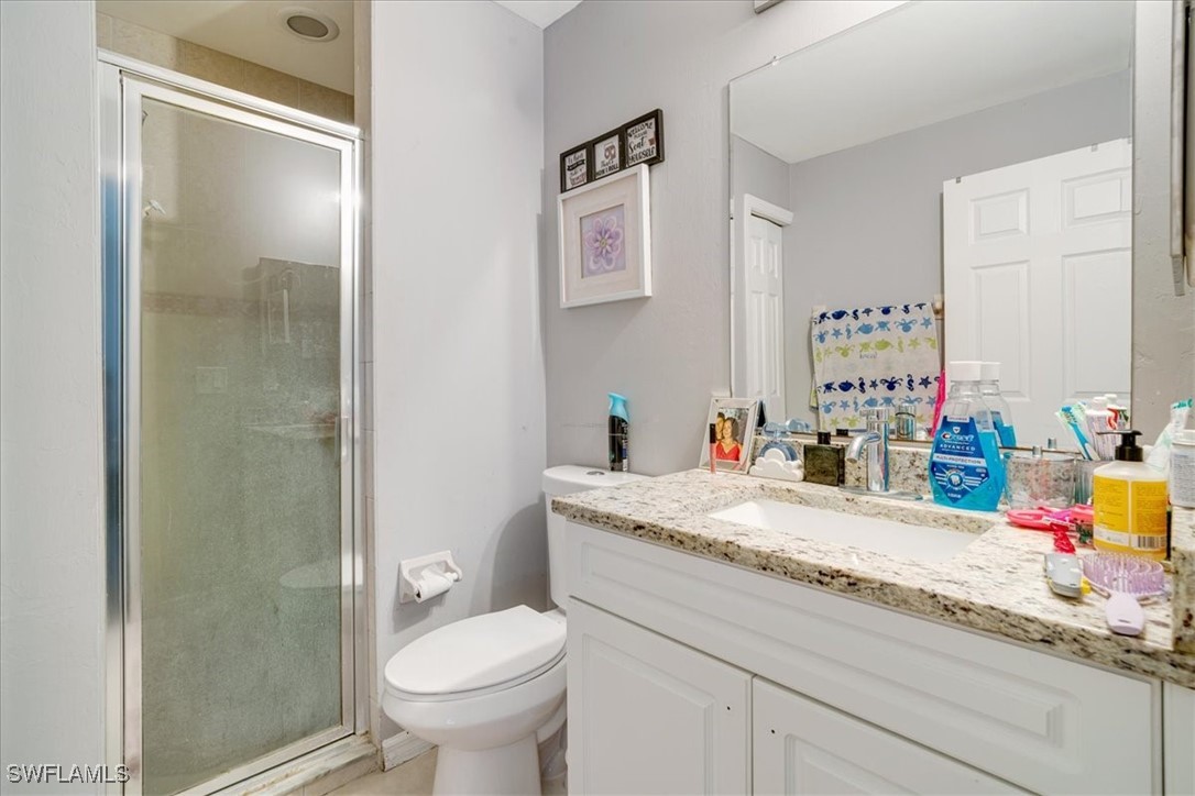 3980 Sunset Road Lehigh Acres, FL 33971 - Photo 14 of 42 a bathroom with a granite countertop sink a toilet and a shower