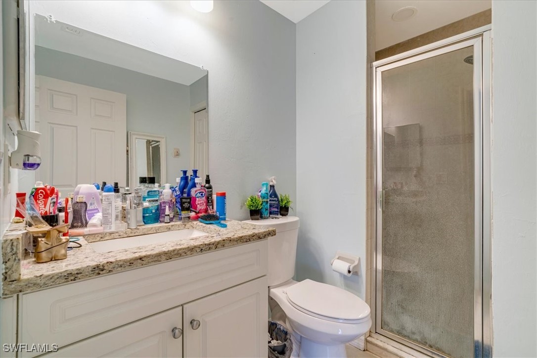 3980 Sunset Road Lehigh Acres, FL 33971 - Photo 25 of 42 a bathroom with a granite countertop sink mirror vanity and toilet