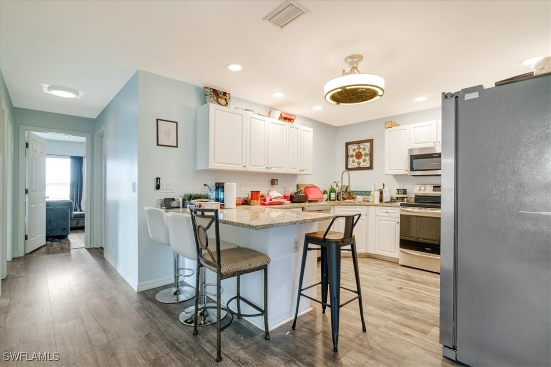 3980 Sunset Road Lehigh Acres, FL 33971 - Photo 4 of 42 a living room with stainless steel appliances kitchen island granite countertop furniture and a wooden floor