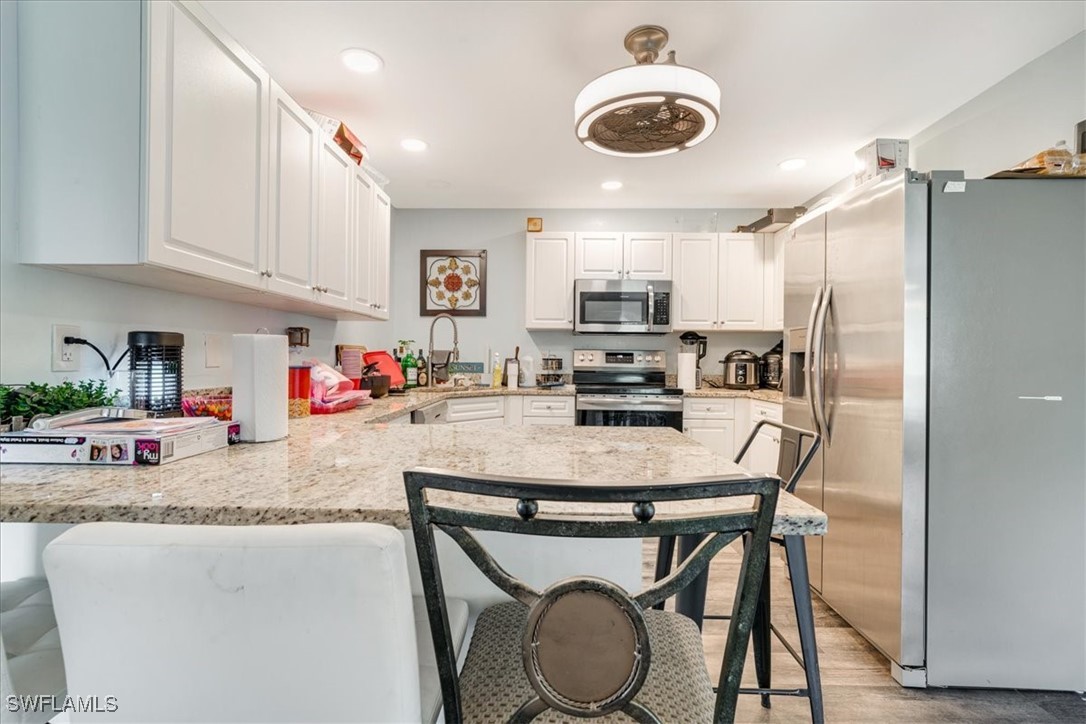3980 Sunset Road Lehigh Acres, FL 33971 - Photo 5 of 42 a kitchen with stainless steel appliances granite countertop a sink a stove a refrigerator and white cabinets