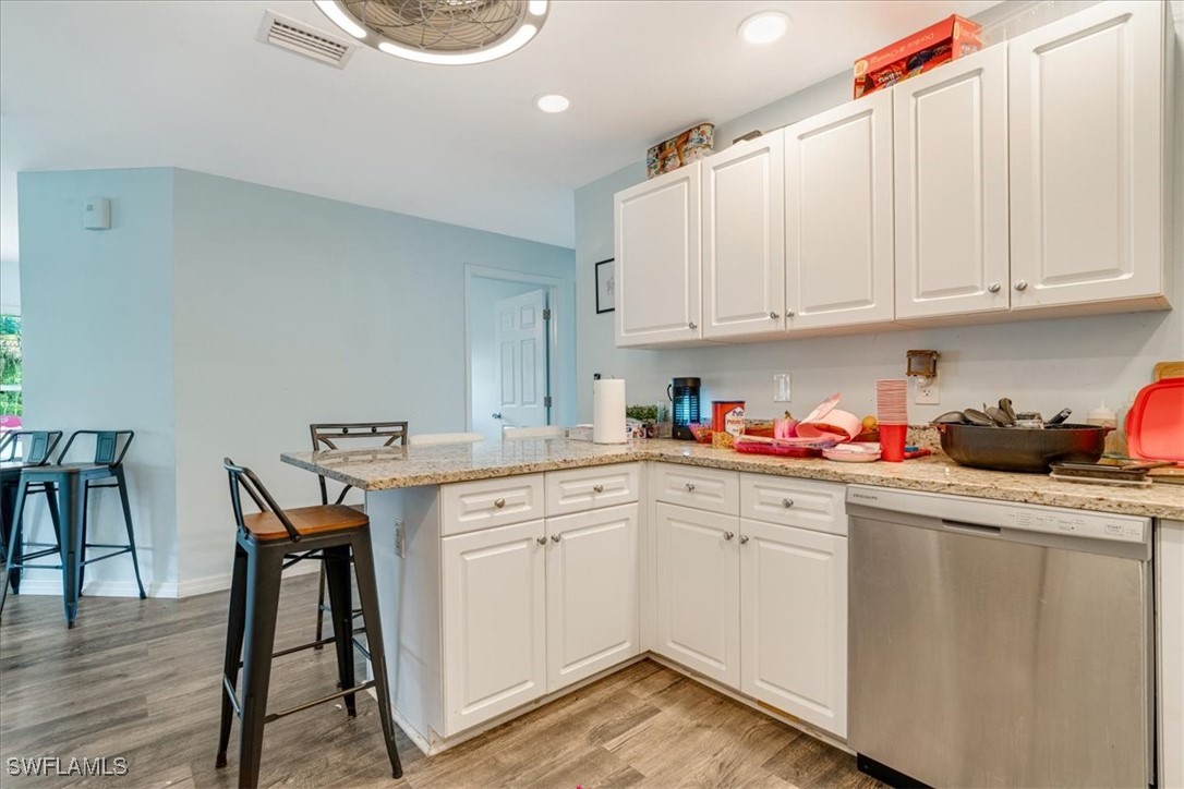 3980 Sunset Road Lehigh Acres, FL 33971 - Photo 6 of 42 a kitchen with stainless steel appliances granite countertop white cabinets a sink dishwasher and a stove with wooden floor
