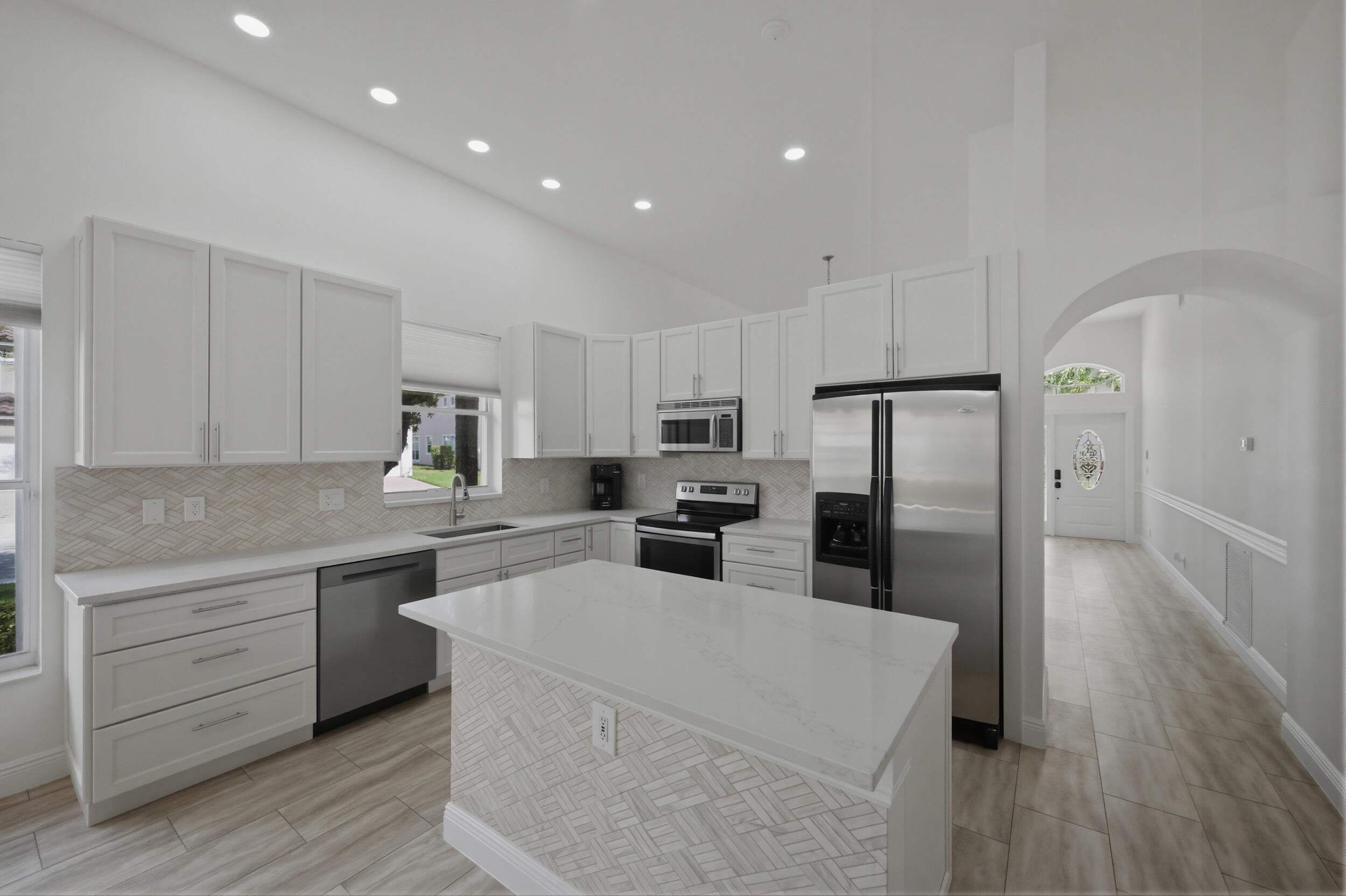 8534 Vía D Oro Boca Raton, FL 33433 - Photo 14 of 34 a kitchen with white cabinets and stainless steel appliances