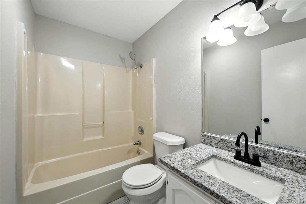 602 Valleyridge Court Decatur, TX 76234 - Photo 17 of 27 a bathroom with a granite countertop sink a toilet and shower