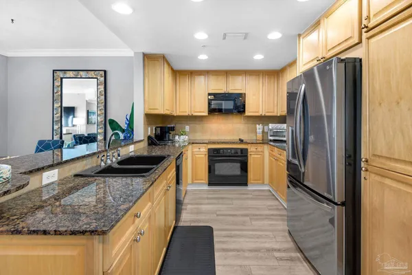 a kitchen with stainless steel appliances granite countertop a sink stove refrigerator and cabinets