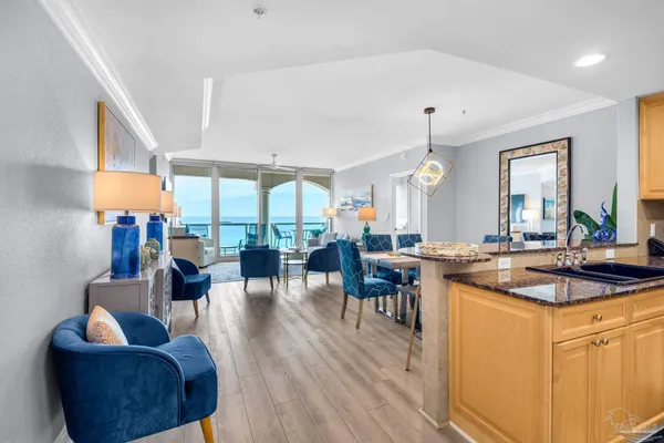 a kitchen with stainless steel appliances granite countertop a stove a sink a dining table and chairs with wooden floor