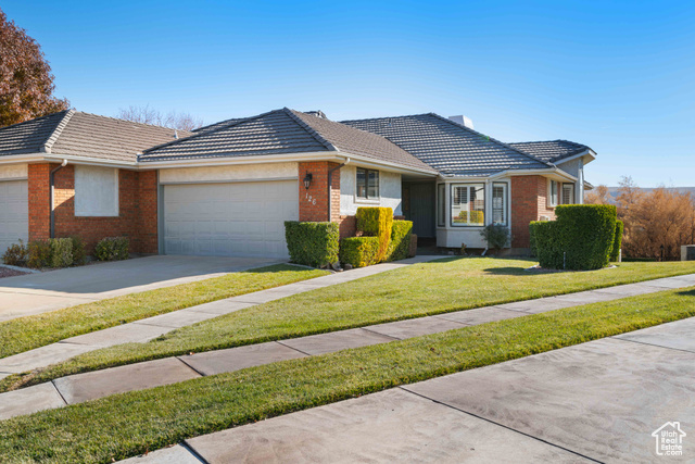 Ranch-style house featuring a front lawn and a garage