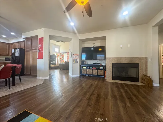 a living room with stainless steel appliances furniture a fireplace and wooden floor