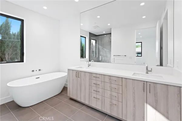 a spacious bathroom with a double vanity sink mirror and bathtub
