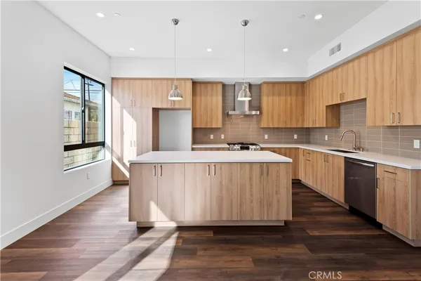 a kitchen with kitchen island granite countertop wooden floors and white cabinets