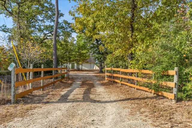 a view of a backyard with wooden fence and large trees