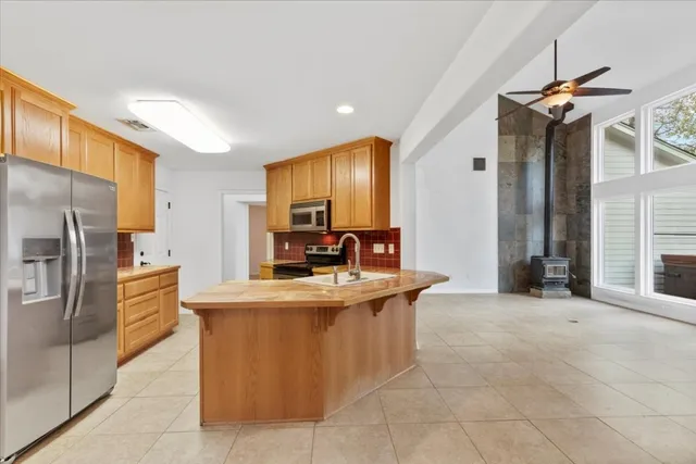 a kitchen with kitchen island a counter top space appliances and a ceiling fan