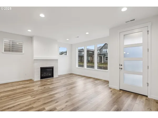 a view of an empty room with wooden floor fireplace and a window