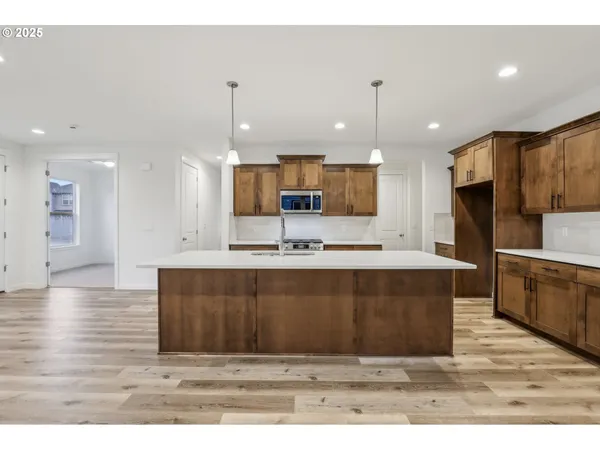 a large kitchen with kitchen island a sink dishwasher a refrigerator and a oven with wooden floor