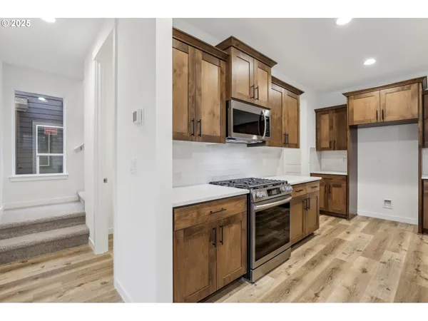 a kitchen with stainless steel appliances granite countertop a stove top oven a refrigerator a sink and a microwave