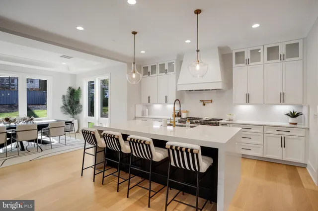 a room with lots of white furniture and wooden floor