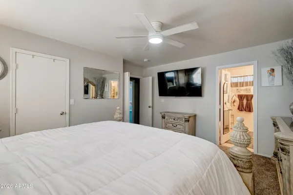 a bedroom with a bed and a flat tv screen on dresser