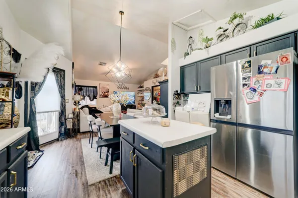 a kitchen with stainless steel appliances granite countertop a refrigerator a sink dishwasher a stove and a dining table with wooden floor